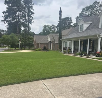 Brick home with a long green lawn, serviced by Florentine Lawn & Spraying Solutions