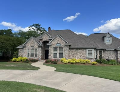 Brick home with a curved driveway and landscaped shrubs